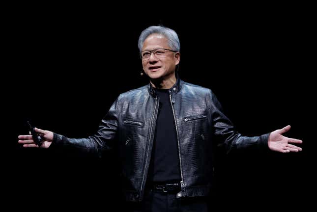 Jensen Huang wearing a black t-shirt and a black leather jacket standing with open arms and smiling